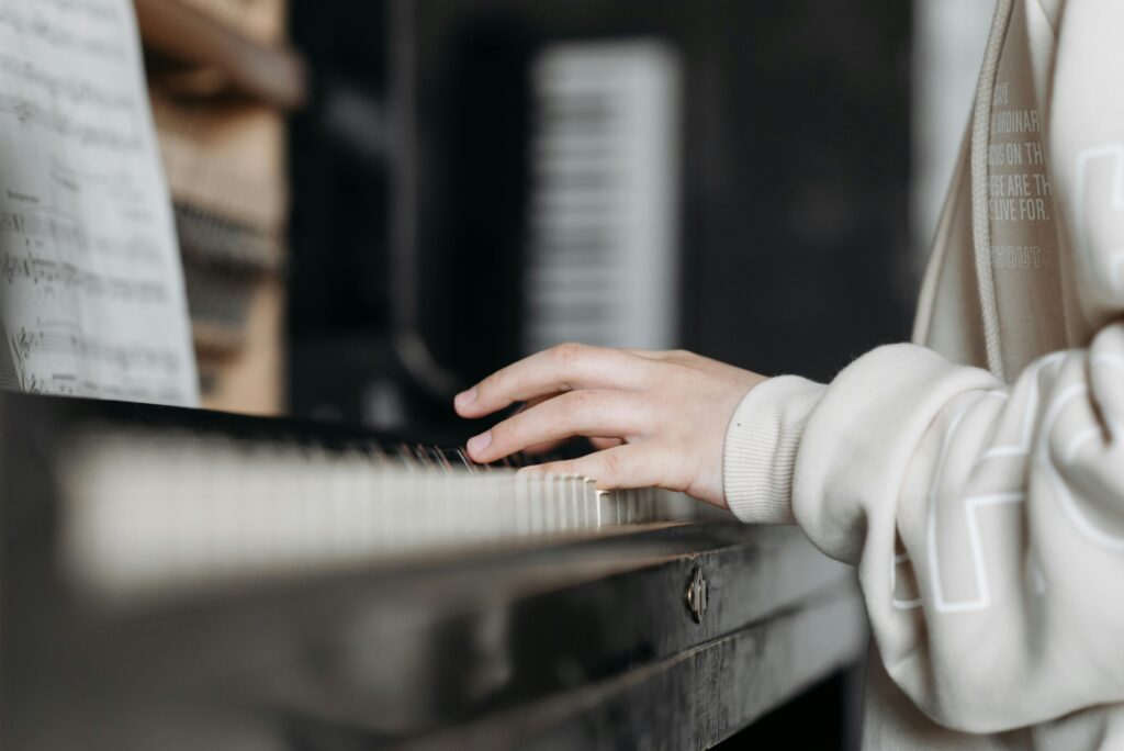 Hands playing piano with sheet music in cozy indoor setting. Perfect for music education visuals.